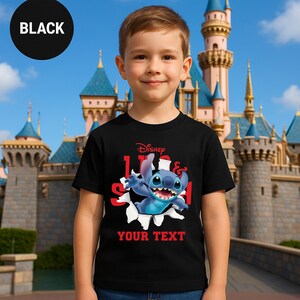 A young boy wearing a black t-shirt with a Disney character printed on it, standing in front of a castle.