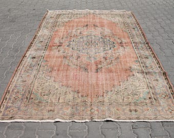 Puede incluir: Alfombra rectangular de aspecto envejecido. Presenta un medallón central en tonos azules y beige sobre un fondo melocotón. El borde, más oscuro, está adornado con intrincados diseños. La alfombra, probablemente de lana, es ideal para un salón.