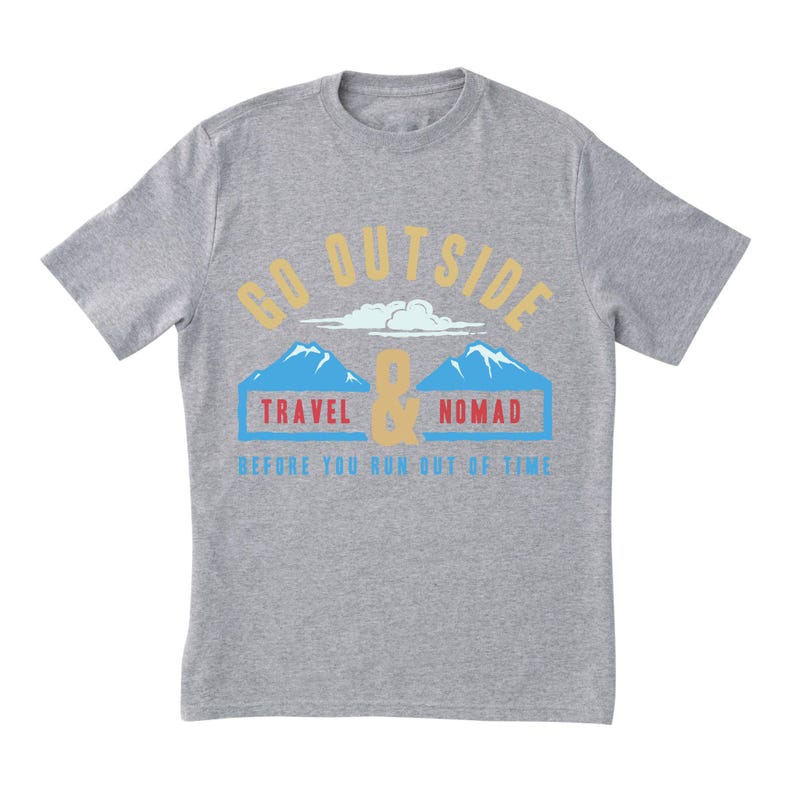 May include: A heather gray t-shirt with a graphic design. The design includes the words "GO OUTSIDE" in gold, with a mountain and cloud illustration, and the words "TRAVEL & NOMAD" in blue and red. The text "BEFORE YOU RUN OUT OF TIME" is in blue.