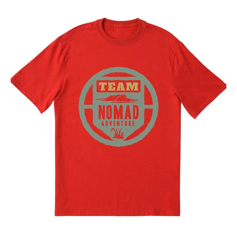 May include: A red crew neck t-shirt with a circular graphic. The graphic features the words "TEAM" and "NOMAD ADVENTURE" in a rectangular and circular design, with a cloud and grass illustration. The shirt is made of a soft material.