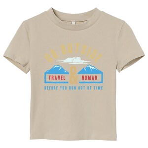 May include: A tan-colored t-shirt with a crew neck. The shirt features the text "GO OUTSIDE" above a graphic of two blue mountains and the words "TRAVEL & NOMAD" in blue boxes. Below is the text "BEFORE YOU RUN OUT OF TIME".