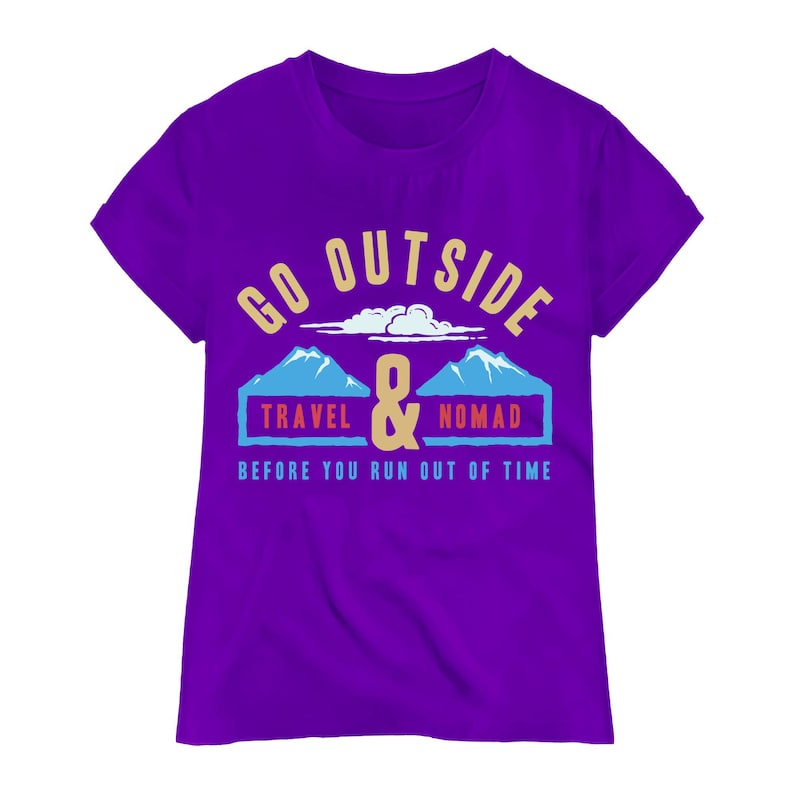 May include: A purple t-shirt with the words "GO OUTSIDE" in gold lettering above a graphic of two blue mountains and the words "TRAVEL & NOMAD" in blue boxes. The text "BEFORE YOU RUN OUT OF TIME" is below the graphic.