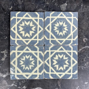 Puede incluir: Cuatro baldosas de cerámica cuadradas con un patrón geométrico de estrella azul y crema. Las baldosas están dispuestas en un cuadrado, mostrando el diseño repetitivo. Las baldosas tienen un acabado brillante, para cocina o baño.