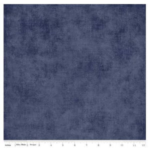 May include: A square piece of dark navy blue fabric with a mottled, textured appearance. A white ruler is visible along the bottom edge, showing a measurement of 12 inches. The text Riley Blake Designs is printed on the ruler.