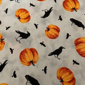 May include: A fabric pattern featuring orange pumpkins and black crows scattered across a light gray background. The pumpkins have detailed shading, and the crows are in various poses. This design is suitable for Halloween-themed crafts.