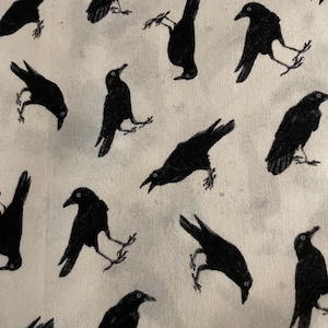 May include: White fabric with a repeating pattern of black crows in various poses. The crows are detailed with visible beaks, eyes, and feet. The overall design has a slightly vintage or gothic aesthetic.