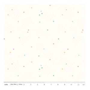 May include: A white fabric featuring a scattered pattern of small, multi-colored polka dots in shades of pink, yellow, and teal. A ruler at the bottom edge shows a scale of 12 inches, with the text Riley Blake Designs printed on the ruler.