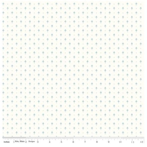 May include: Cream-colored fabric with a repeating pattern of small, light blue floral motifs and tiny brown dots. The design is evenly spaced across the surface. A ruler with inch measurements is at the bottom.