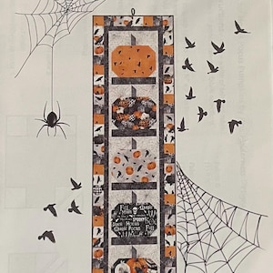 May include: A Halloween-themed quilt pattern titled "Hocus Pocus Pumpkins!" features orange pumpkins, crows, and spiderwebs. The project size is 16" x 58". The design includes the text "Full Moon", "Spooky", and "Magic Pocus".