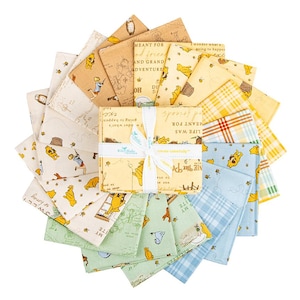 May include: A collection of Winnie the Pooh themed fabric squares in various colors, including yellow, blue, and green. The fabric features illustrations of Pooh Bear and related characters, along with text. The squares are tied together with a white ribbon.