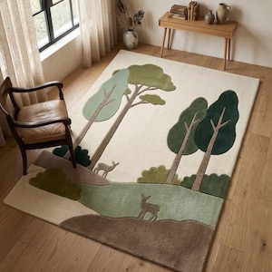 May include: A rectangular area rug featuring a cream background with a tufted forest landscape design. The rug displays stylised green trees, brown ground sections, and two small deer silhouettes in shades of brown and light green.