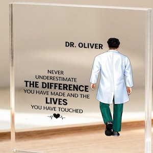 Op de afbeelding: Een vierkante acrylplaat met een bedrukte illustratie van een arts in een witte jas en groene broek die wegloopt. De tekst luidt DR. OLIVER en NEVER UNDERESTIMATE THE DIFFERENCE YOU HAVE MADE AND THE LIVES YOU HAVE TOUCHED.