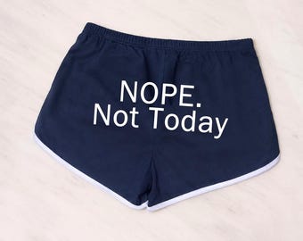 Puede incluir: Pantalones cortos deportivos de color azul marino con una cintura elástica blanca y ribete blanco a lo largo de las aberturas de las piernas. El texto NOPE. Not Today está impreso en letras blancas mayúsculas y minúsculas.