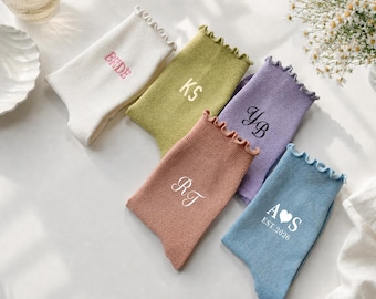 May include: Five pairs of ruffled-top socks in white, olive green, lavender, terracotta, and blue. The white pair features the text BRIDE, the olive pair has KS, the lavender pair has YB, the terracotta pair has RT, and the blue pair has A heart S EST.2026.