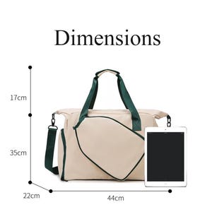 May include: Beige duffel bag with dark green accents. The bag has a shoulder strap and handles. Dimensions are 17cm high, 35cm wide, 22cm deep, and 44cm long. The word "Dimensions" is printed at the top.