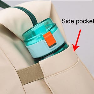 May include: A close-up of a beige backpack with a teal zipper and a side pocket holding a teal and orange water bottle. The text "Side pockets" is visible with an arrow pointing to the pocket.