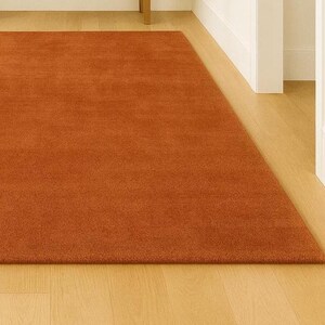 Earthy warm tone rug adding color to neutral Scandinavian bedroom