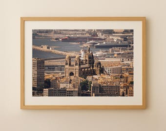 Puede incluir: Impresión enmarcada con un paisaje urbano, una gran catedral y un puerto. La imagen muestra una vista detallada de edificios, un puerto con barcos y un cielo despejado. El marco es de madera clara.