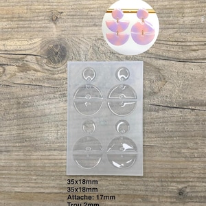 Peut inclure: Un moule à boucles d'oreilles en silicone transparent avec plusieurs modèles, dont des formes en demi-cercle et circulaires. Le moule est à côté d'une paire de boucles d'oreilles finies roses et violettes. Le texte sur l'image indique : 35x18mm, Attache: 17mm, Trou 2mm.