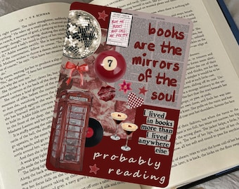 Op de afbeelding: Een decoratieve bladwijzer met de tekst "books are the mirrors of the soul" en andere tekst, samen met een discobal, een biljartbal en een telefooncel-illustratie, op een open boek.