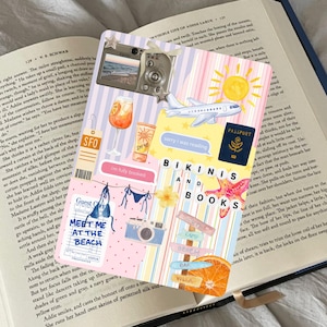 May include: Bookmark with travel-themed illustrations, including a camera, airplane, passport, and the text "Bikinis and Books." The design features a beach theme with a sun, orange slice, and the phrase "Meet Me at the Beach."