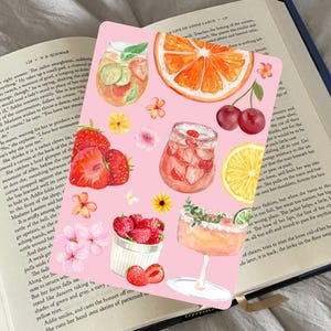 Könnte beinhalten: Eine rosa Karte mit Aquarellillustrationen von erfrischenden Sommergetränken, darunter Cocktails, mit Früchten angereichertes Wasser und frisches Obst wie Erdbeeren, Kirschen und eine Orangenscheibe. Florale Akzente vervollständigen das Design.