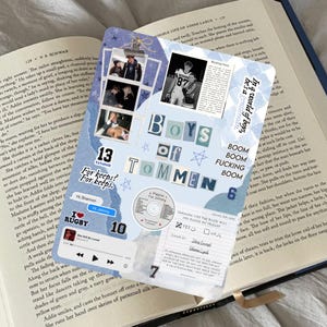 Könnte beinhalten: Eine dekorative Scrapbook-Seite mit Fotos, Text und Aufklebern. Die Seite zeigt die Worte "Boys of Tommen" und "For keeps?" in einem blau-weißen Farbschema. Im Hintergrund ist ein Buch zu sehen.