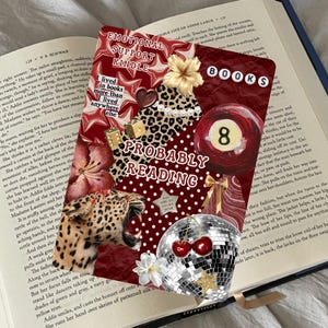 Könnte beinhalten: Ein dekoratives Buchzubehör mit einem Collage-Design. Die Collage enthält einen Leopardenmuster, eine Discokugel, Kirschen und den Text "Probably Reading". Der Hintergrund ist ein Buch mit Text.