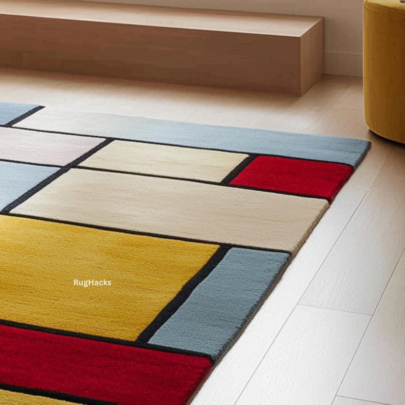 May include: A rectangular area rug with a geometric design. The rug features a pattern of rectangles in red, yellow, beige, and light blue, outlined with black lines. The text "RugHacks" is visible on the rug.