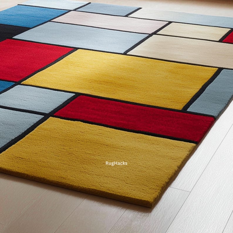 May include: A rectangular area rug with a geometric design. The rug features a pattern of colorful rectangles in shades of yellow, red, blue, and gray, outlined with black borders. The rug is made of a soft, textured material.