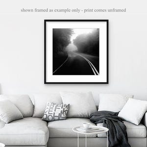 May include: Black and white framed print of a road disappearing into a foggy forest. The road has white lines and is surrounded by trees. The text at the top says "shown framed as example only - print comes unframed."