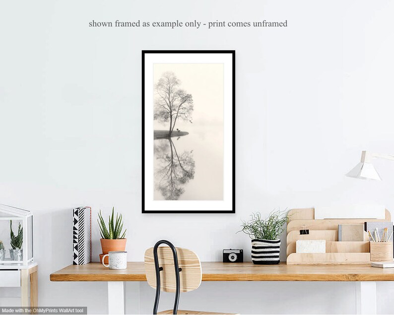 May include: A black and white photograph of a tree reflected in a still body of water. The tree is bare and the water is calm, creating a serene and minimalist image.