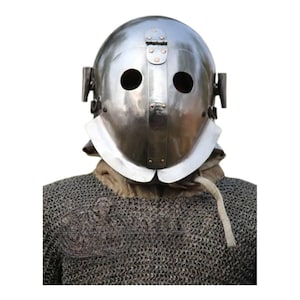 May include: A shiny silver metal helmet with two eye holes and a hinged visor. The helmet features a neck guard and is worn over a chainmail shirt. The background is plain white.