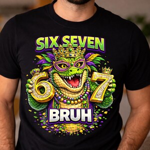 May include: Black t-shirt with a colorful graphic featuring a cartoon alligator wearing a crown and holding the numbers 6 and 7. The text "SIX SEVEN" and "BRUH" are also displayed.