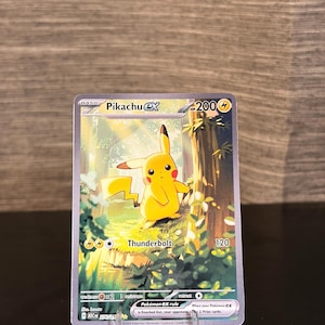 May include: A Pikachu EX Pokémon trading card. The card features a yellow Pikachu character in a forest setting with the word "Thunderbolt". The card has a 200 HP rating and other game details.