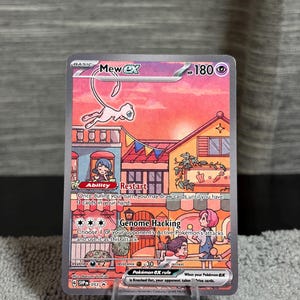 May include: A Mew ex trading card featuring a pink Mew flying above a colorful town scene with buildings, bunting, and people. The card displays 180 HP, the Restart ability, and the Genome Hacking attack. Text includes Mew ex, Restart, Genome Hacking, and SVP 053.