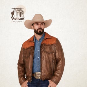 May include: A brown leather jacket with a tan leather yoke and collar. The jacket has two chest pockets and a front zipper. The image also features a cowboy hat and the text "Vellum Wear Jackets".