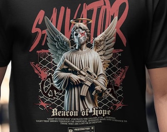May include: Black t-shirt featuring a graphic of an angel statue with a halo, wings, and a rifle. The design includes the word "SAVATOR" in red, along with the text "Beacon of Hope" and other text. The shirt has a crew neck.