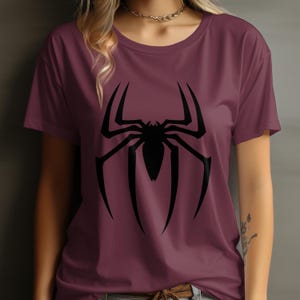 Puede incluir: Camiseta burdeos de cuello redondo con un gran gr&aacute;fico de ara&ntilde;a negra. El dise&ntilde;o de la ara&ntilde;a es sim&eacute;trico con patas largas y puntiagudas y un cuerpo central. La camiseta est&aacute; hecha de un material suave.