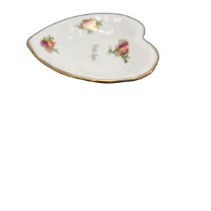 May include: Heart-shaped white dish with a gold rim, featuring floral designs and the text "With Love". The dish has a delicate appearance, suitable for serving small items or as a decorative piece.