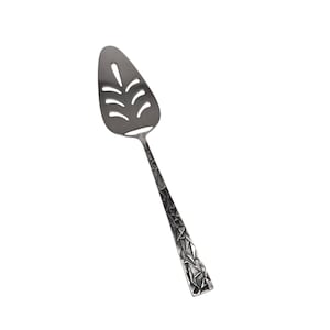 May include: A silver-colored pie server with a leaf-shaped design cut into the blade. The handle has a textured, geometric pattern. The server is designed for serving pies, cakes, or other baked goods.