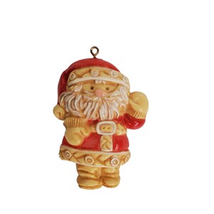 May include: A vintage Christmas ornament featuring a Santa Claus figure with a white beard and a red and white hat. The ornament is made of plastic and has a gold loop for hanging.