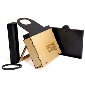 Peut inclure: Une boîte noire et beige avec une poignée et un logo découpé au laser portant l'inscription "ANA LOG" sur le panneau avant. La boîte présente des joints emboîtables, un couvercle rectangulaire noir séparé et un élément latéral noir.