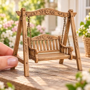 May include: A miniature wooden swing set featuring a bench suspended by metal chains from an arched frame. The structure is decorated with carved floral motifs on the top arch and side posts, showcasing a brown wood grain finish throughout.