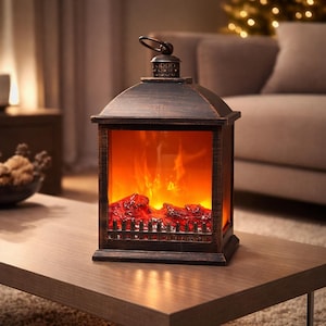 Puede incluir: Una linterna decorativa con efecto de chimenea falsa. La linterna tiene un acabado en bronce oscuro y un asa en la parte superior. En el interior, un fuego simulado brilla con luz naranja y roja, creando un ambiente cálido. La linterna está sobre una mesa de madera.