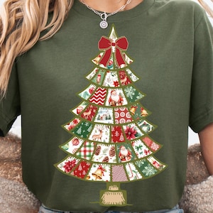 Puede incluir: Camiseta verde oliva con un diseño de árbol de Navidad. El árbol está compuesto por varios patrones festivos, incluyendo Papá Noel, renos y copos de nieve. Un gran lazo rojo adorna la parte superior del árbol. Estilo de camisa cómodo e informal.