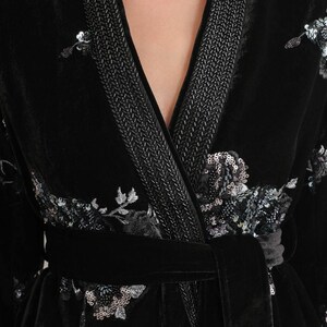 May include: Black velvet robe with floral sequin embroidery and a matching belt. The robe features a braided trim along the lapels and cuffs. A luxurious garment for lounging or special occasions.