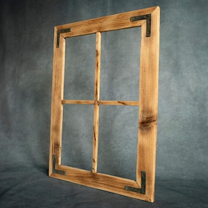 Könnte beinhalten: Ein rustikaler Holzfensterrahmen mit natürlicher Oberfläche. Der Rahmen hat vier Scheiben und Eckwinkel aus Metall. Die Holzmaserung ist sichtbar, und der Rahmen hat ein leichtes Used-Aussehen.