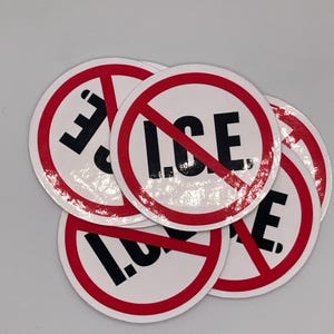 May include: A collection of round stickers with a white background, a red border, and the text "I.C.E." in black, crossed out with a red line. The stickers are overlapping.