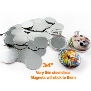 May include: A collection of silver, 3/4-inch steel discs, with the text "Very thin steel discs. Magnets will stick to them." Also shown are two pendant trays and two finished pendants with colorful designs.